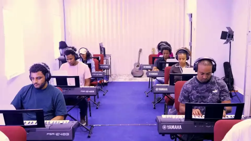 A teacher guiding students through keyboard practice at Misgana